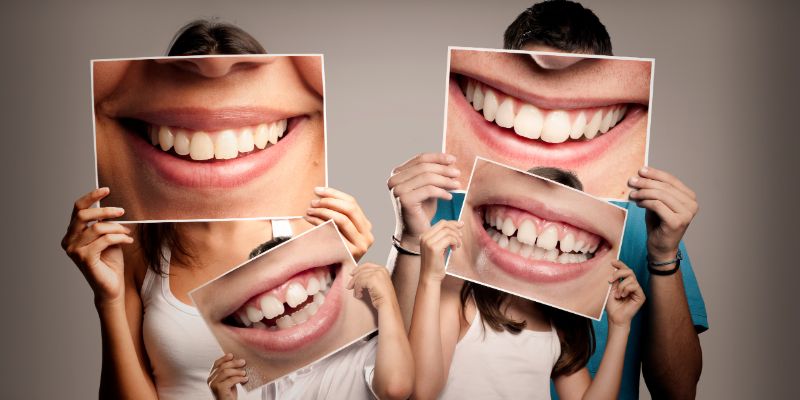 A family of four holding up pictures of smiles