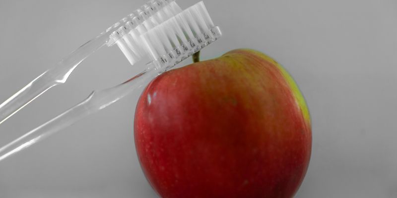 apple with two toothbrushes on top of it
